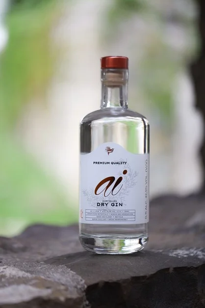 Boca suhog gina stoji na kamenoj površini, s etiketom: "ai PREMIUM QUALITY DRY GIN".